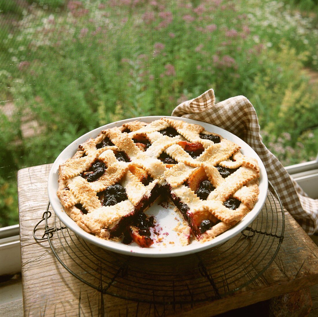 A Blueberry Nectarine Pie on a Window Sill with Slice Removed