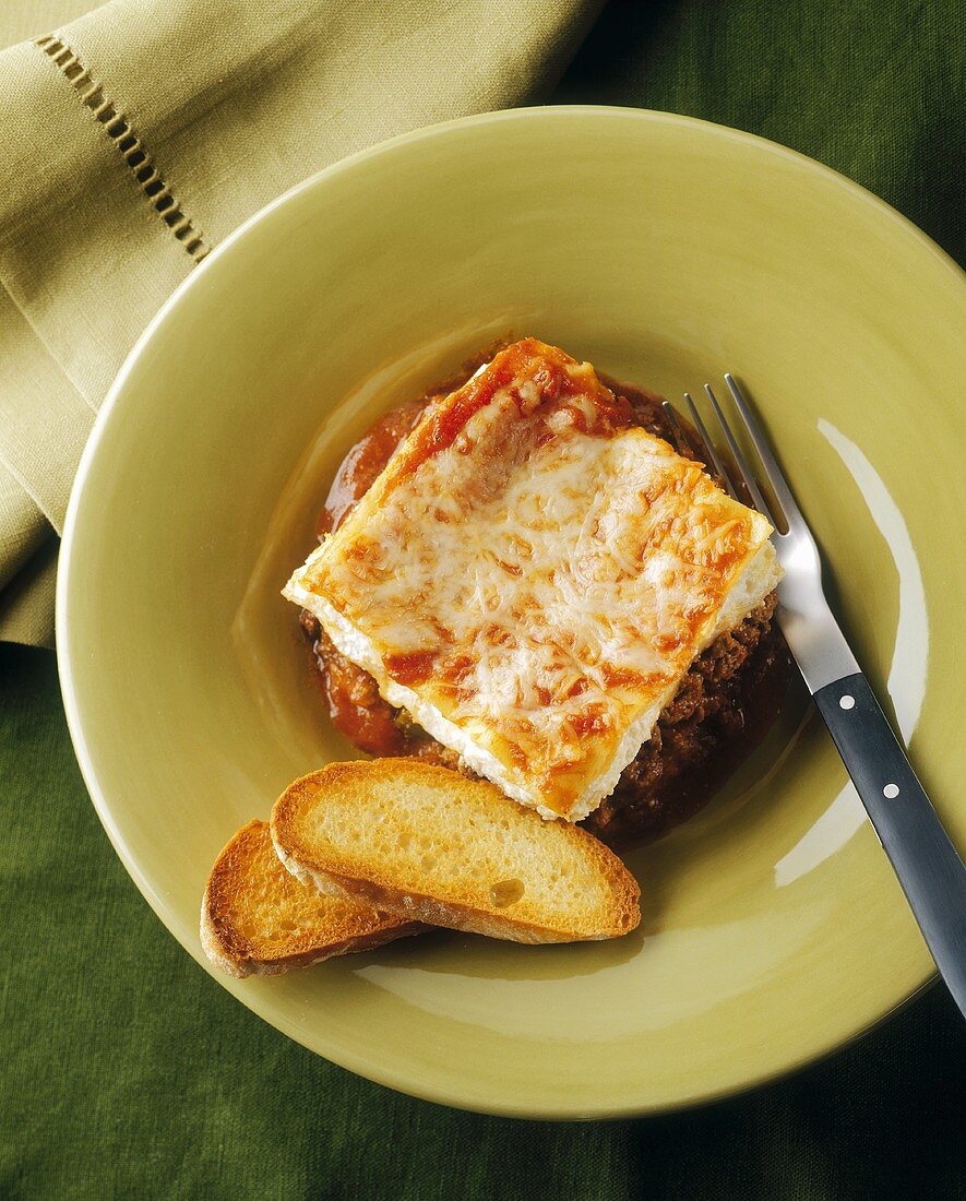 Portion of baked mince dish with toasted baguette
