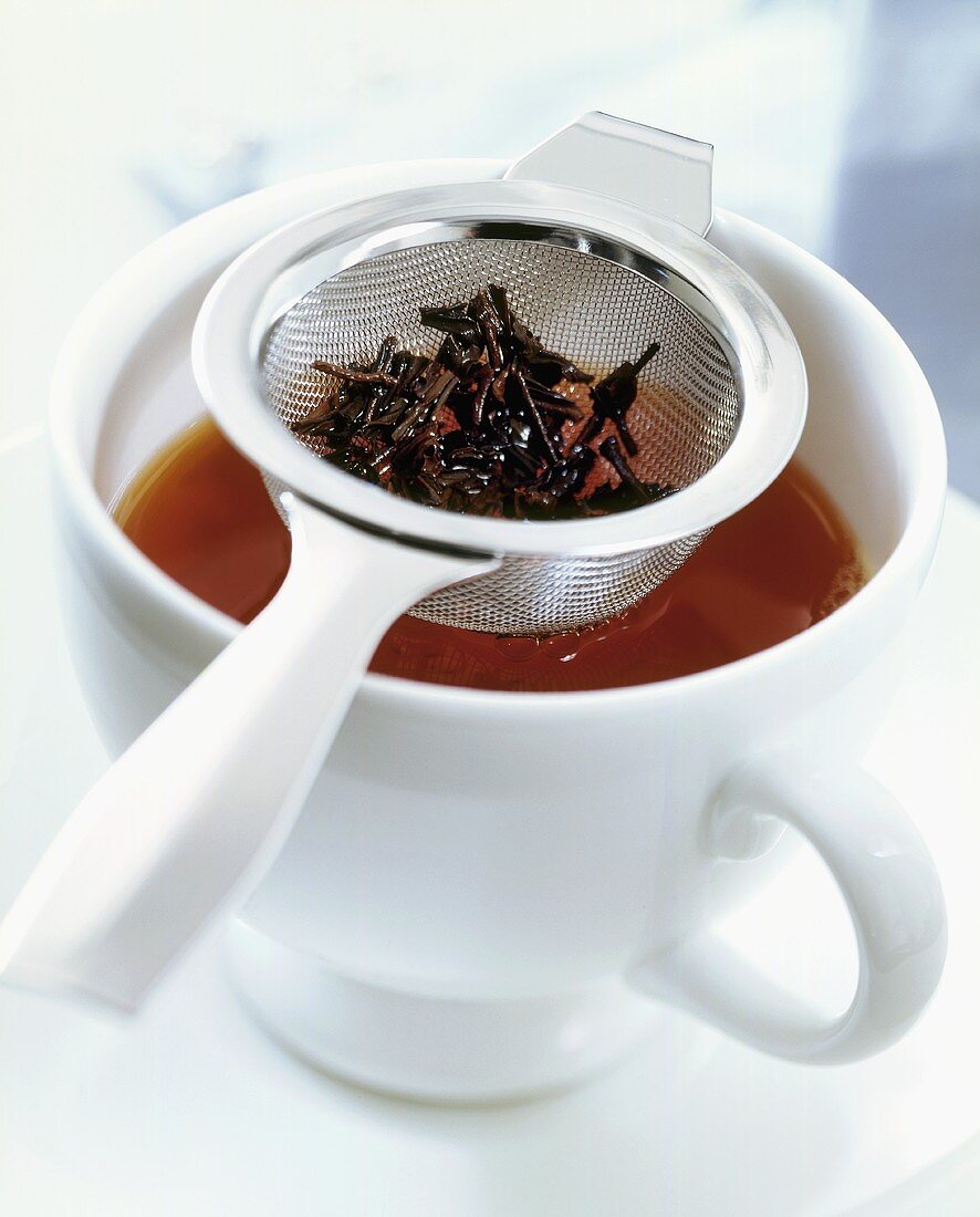 Tea leaves in strainer on teacup