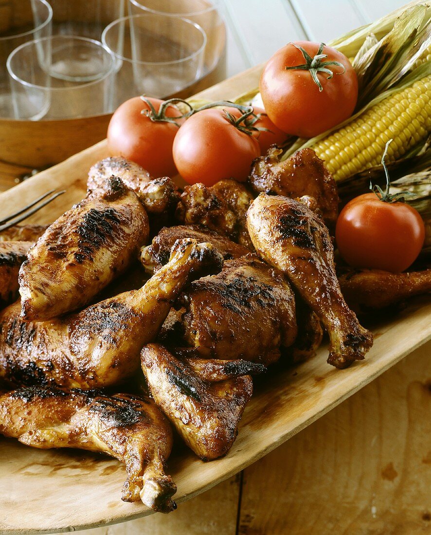 Gegrillte Hähnchenteile mit Tomaten und Maiskolben auf Platte