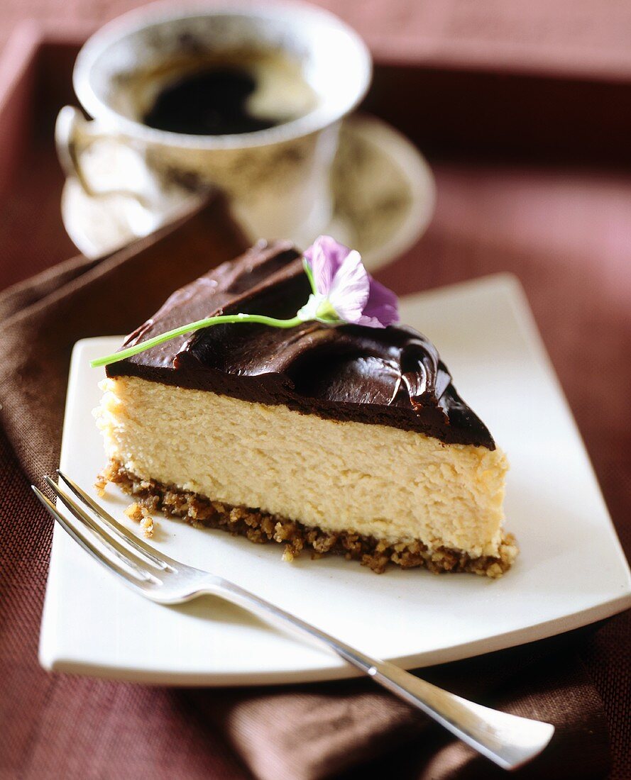 A piece of cheesecake with chocolate icing