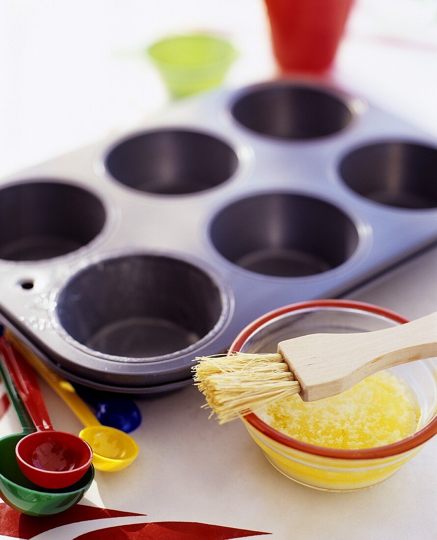 Muffinform und zerlassene Butter mit Pinsel