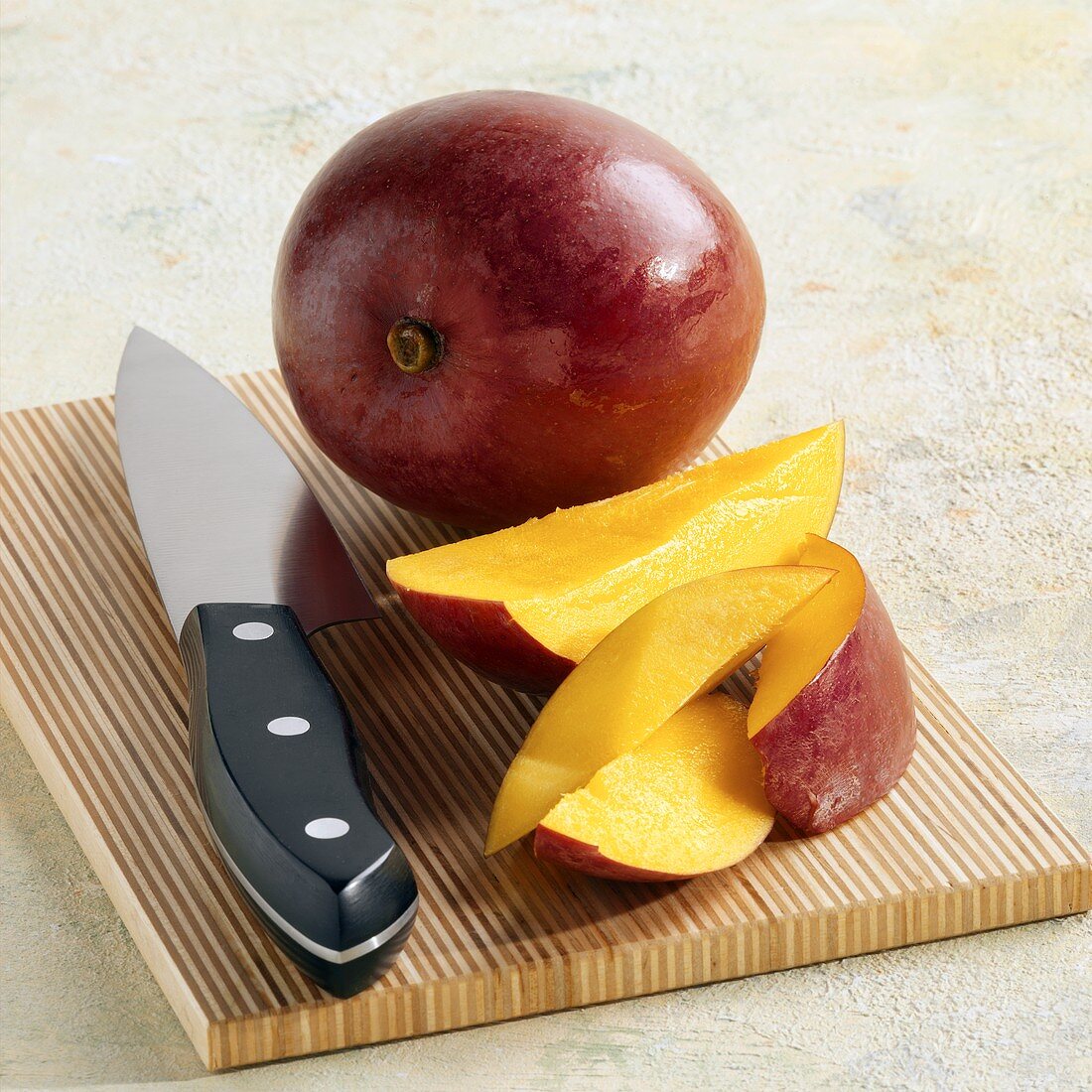 Whole Ripe Mango on a Cutting Board with Mango Slices, Knife