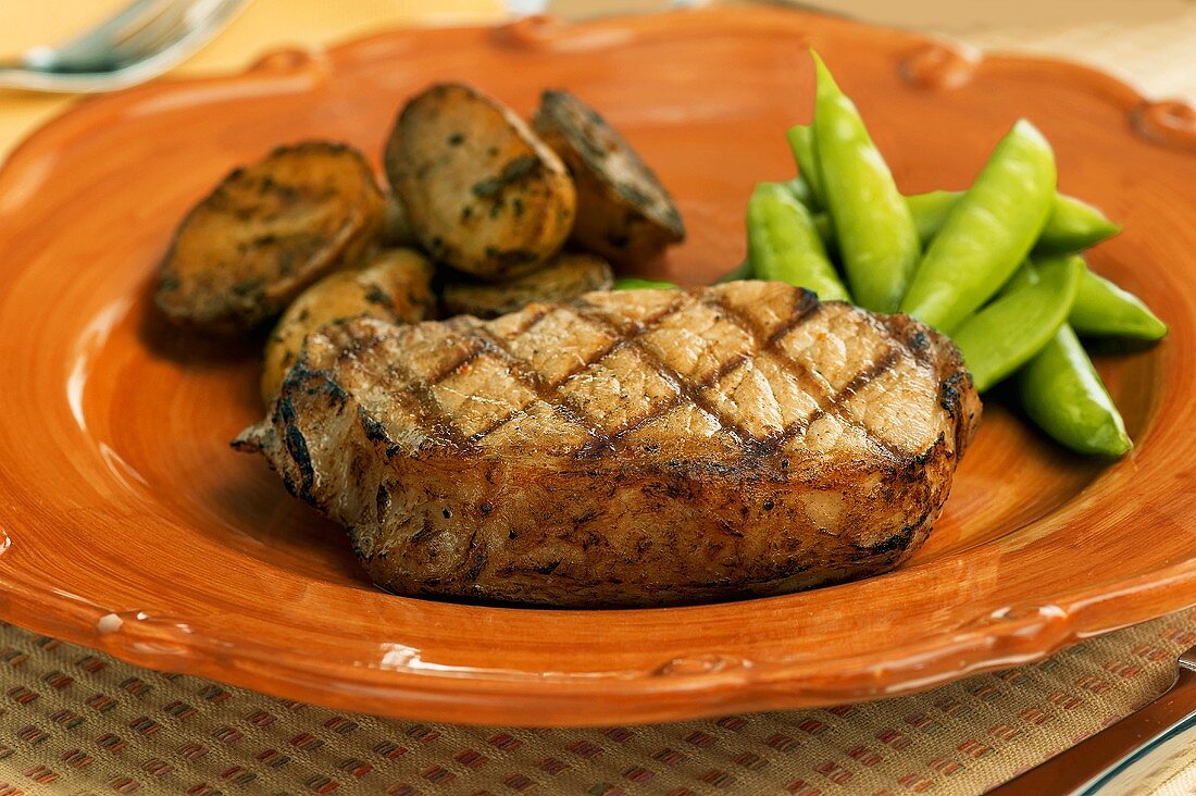 Grilled pork chop with potatoes and sugar snap peas