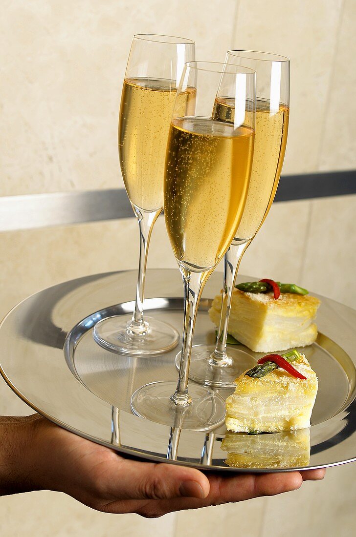 Hand Holding a Silver Tray with Glasses of Champagne and Appetizers