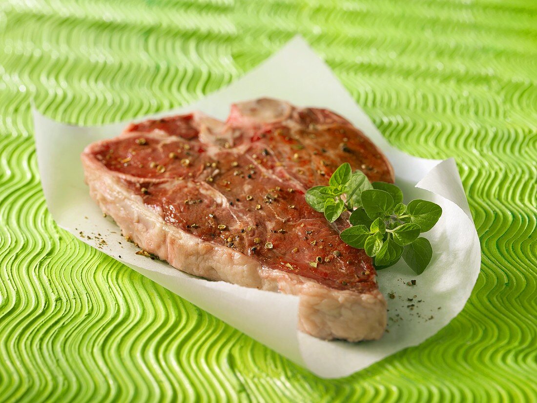 Rohes T-Bone-Steak mit Pfeffer auf Papier