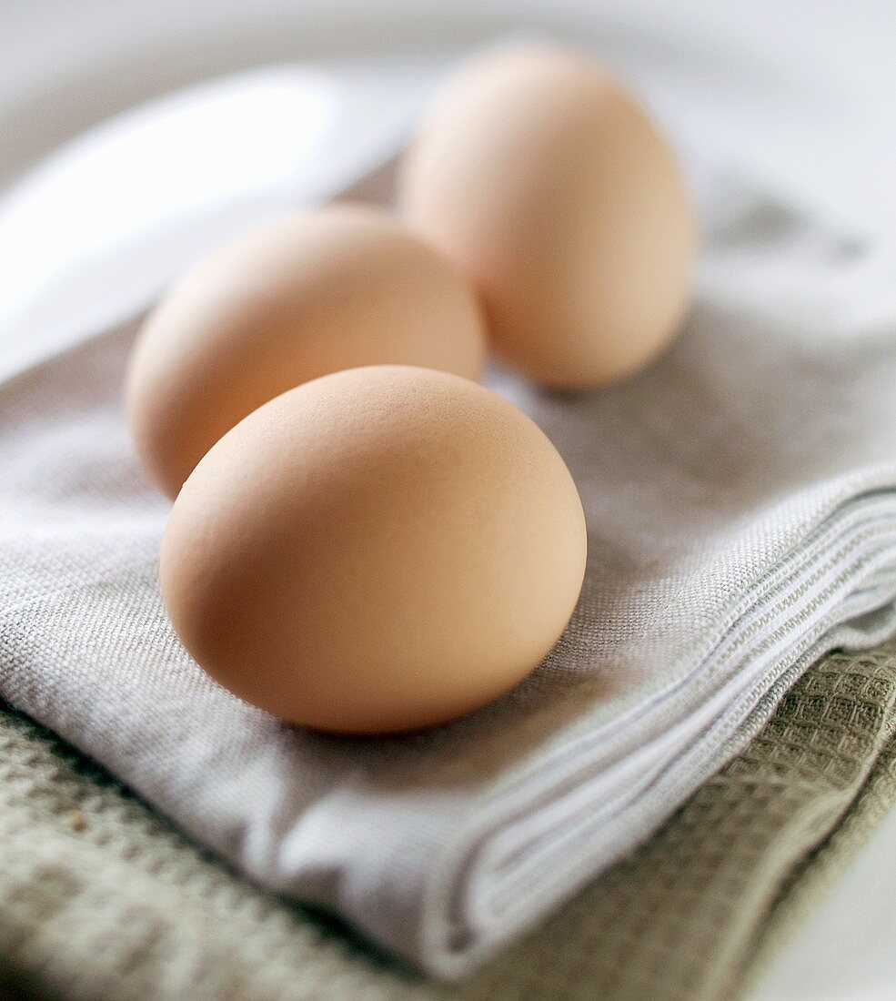 Drei braune Eier auf Geschirrtuch