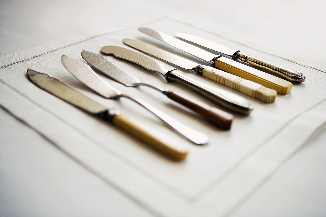 Various butter knives on fabric napkin