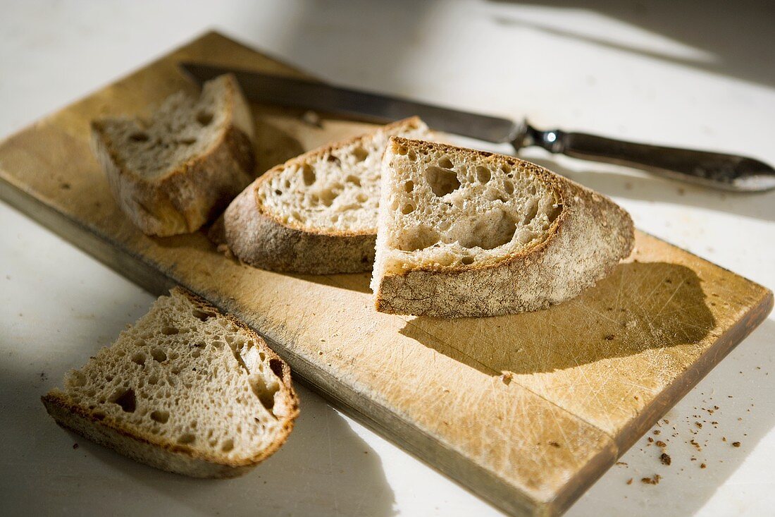 Schneidebrett mit vier Brotscheiben und Messer