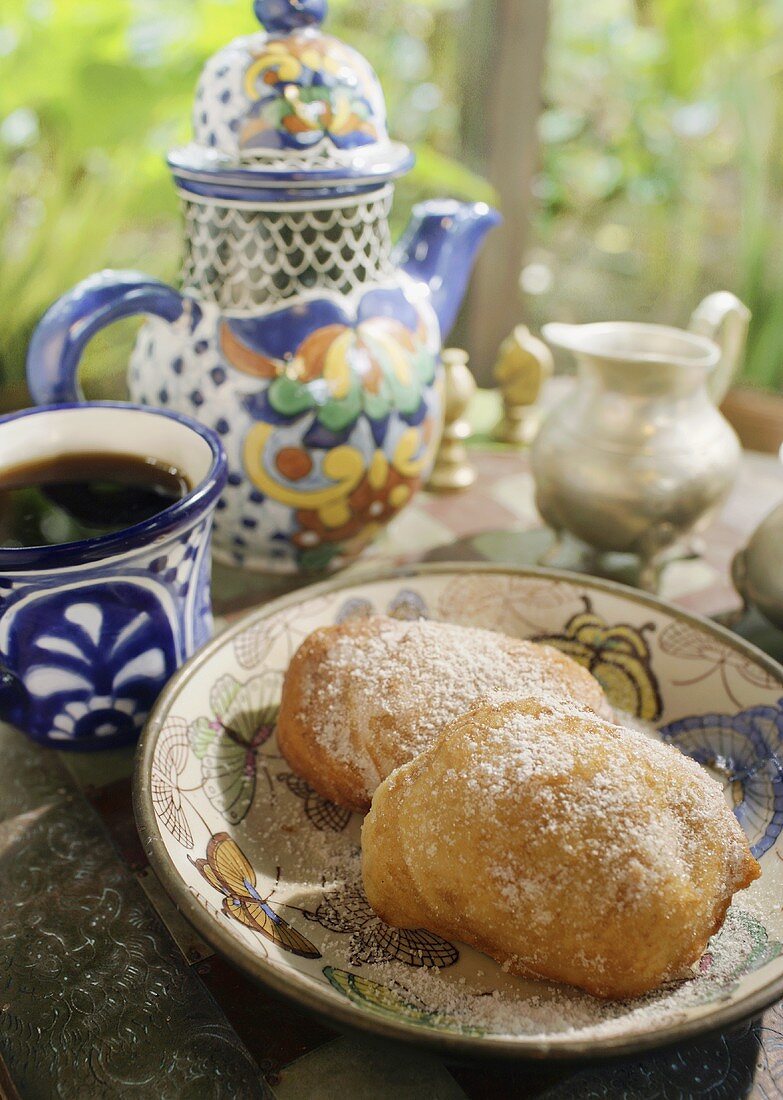 Sweet pastries with icing sugar, coffee and coffee pot