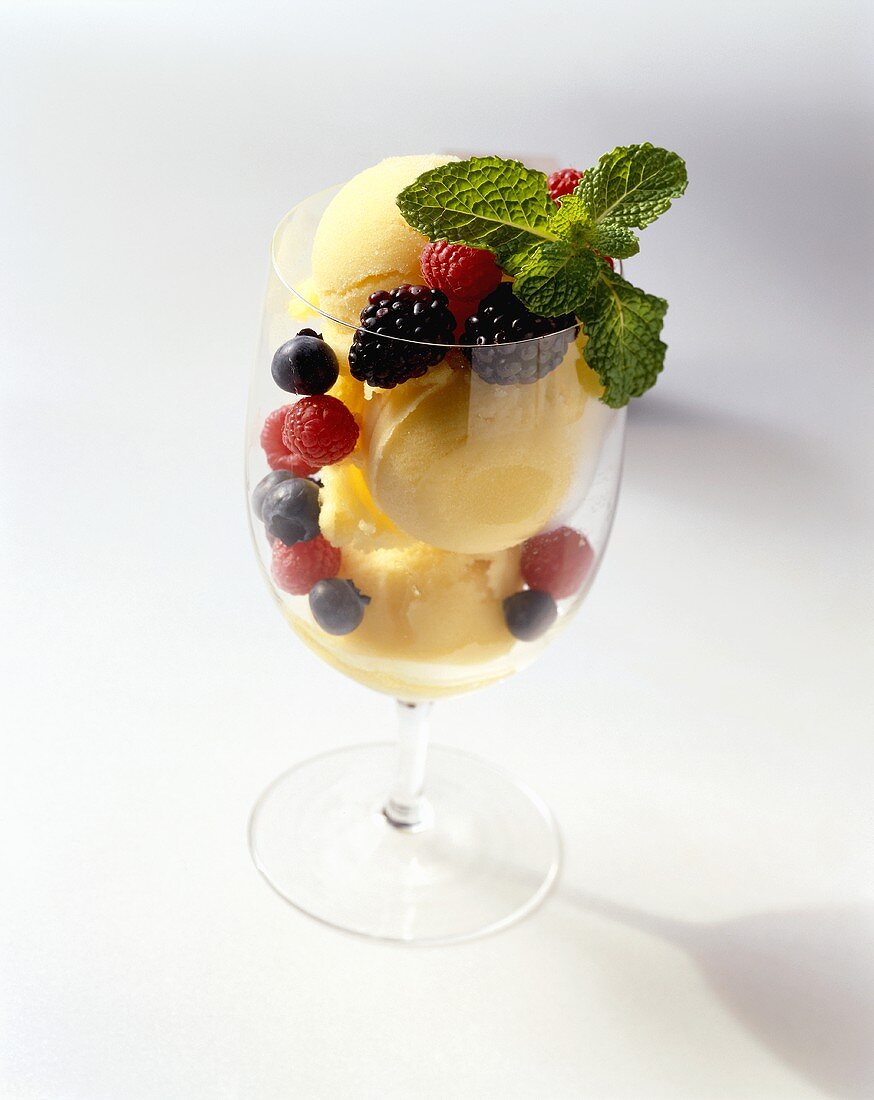 Zitronensorbet mit frischen Beeren in Stielglas