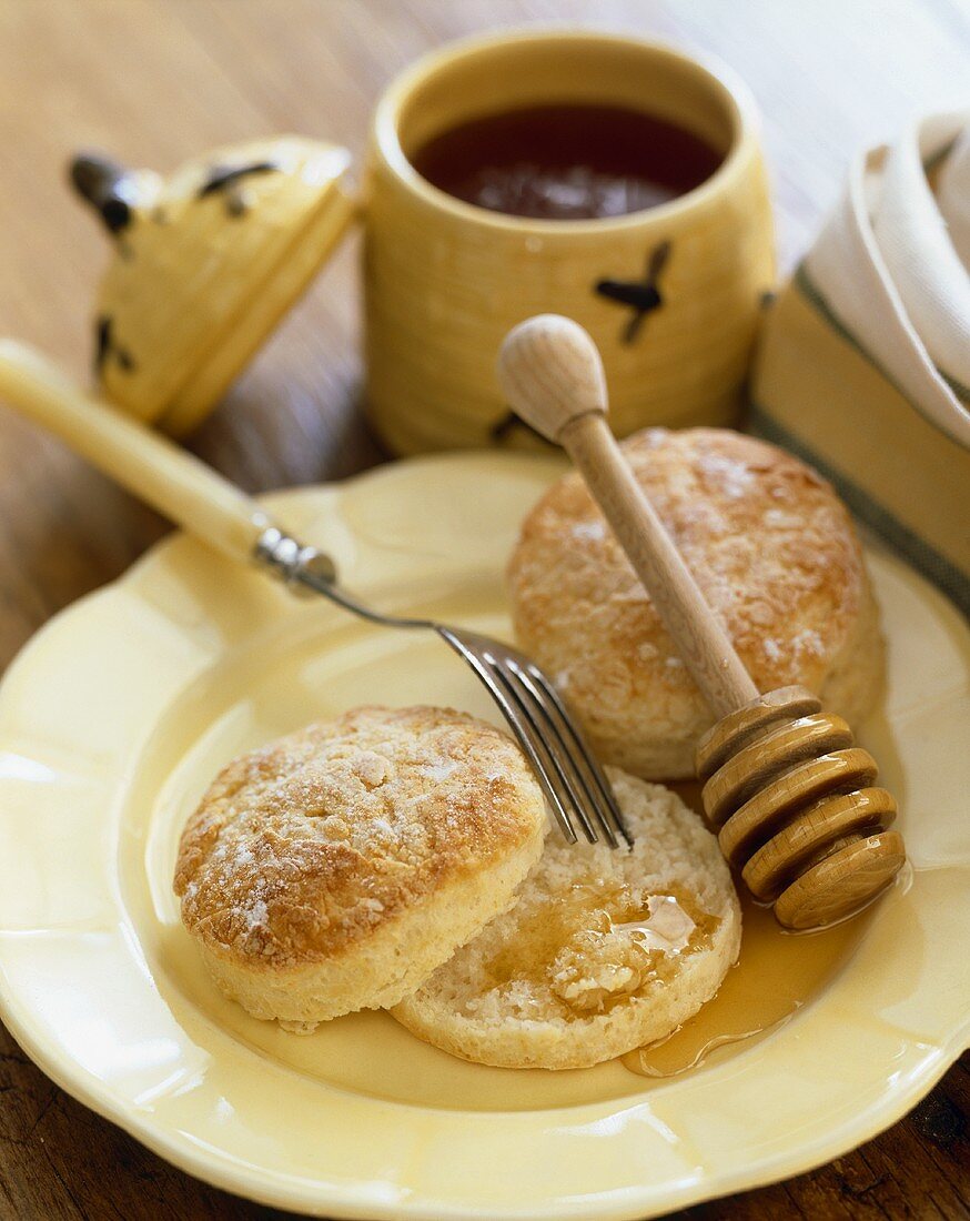 Two Fork Split Biscuits on a Plate; One Split in Half with Honey; Honey Dipper and Fork