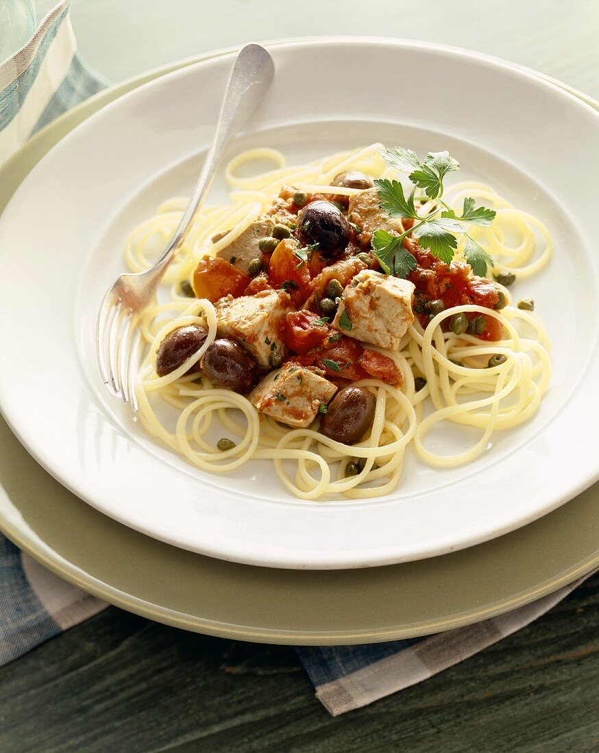 Spaghetti Tossed with Tuna, Olives and Fresh Tomatoes on a White Plate with a Fork