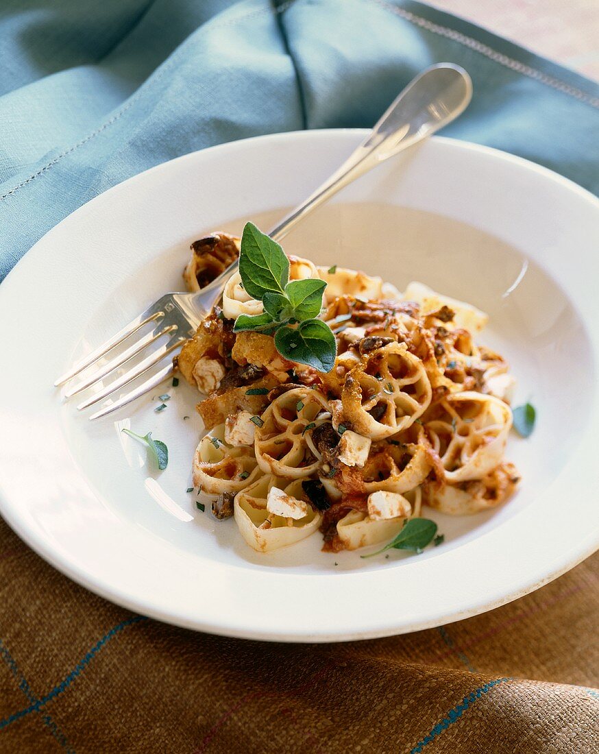 Wagon Wheel Pasta with Fresh Tomato Sauce with Olives and Feta Cheese in a White Bowl; Fork