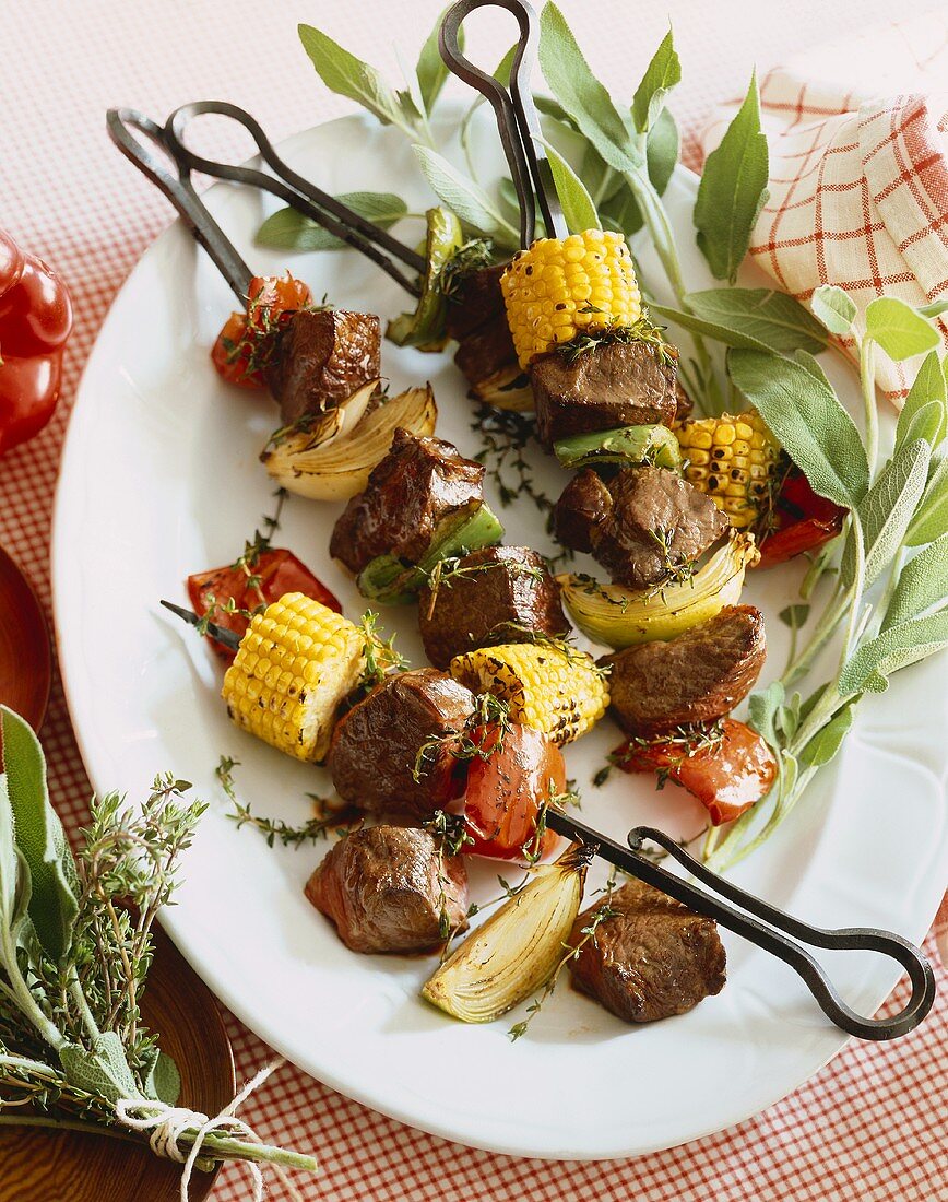 Beef and Vegetable Kabobs on a White Platter, Fresh Herbs