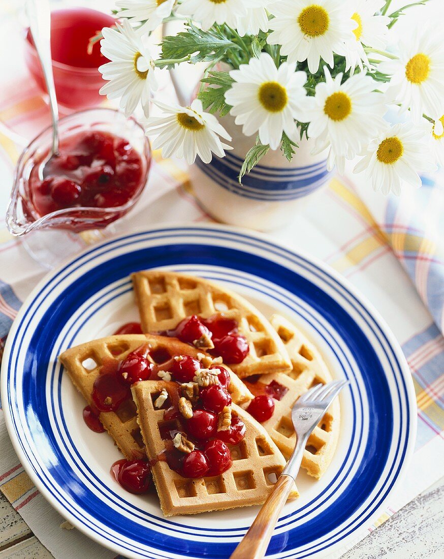 Plate of Waffles Topped with Cherry Sauce; Fork; Pitcher of Cherry Sauce with Spoon; Daisies