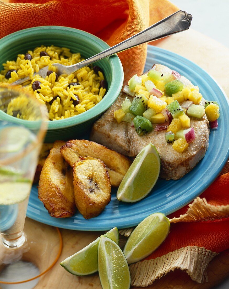 Tuna Topped with Mango Kiwi Salsa with Fried Plantains and a Bowl of Rice and Beans; Lime Wedges