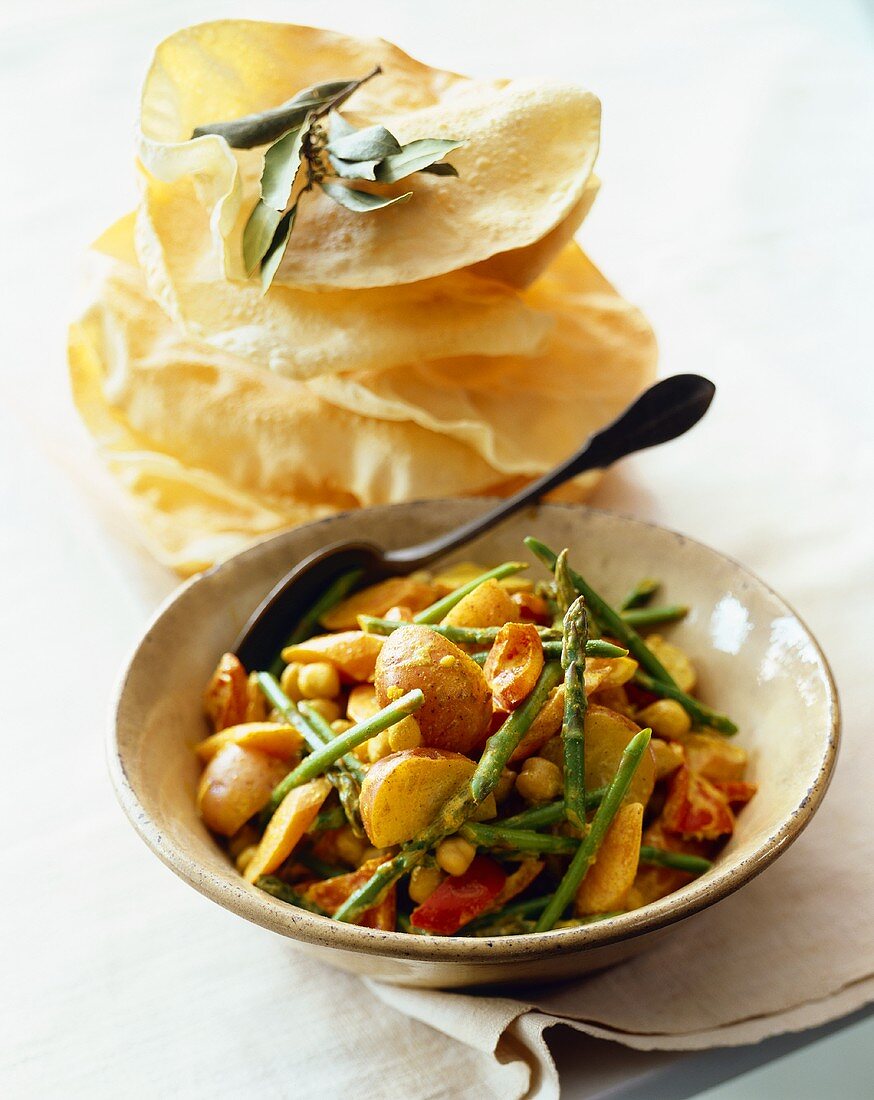 Bowl of Curried Vegetables with Spoon; Stack of Flat Bread