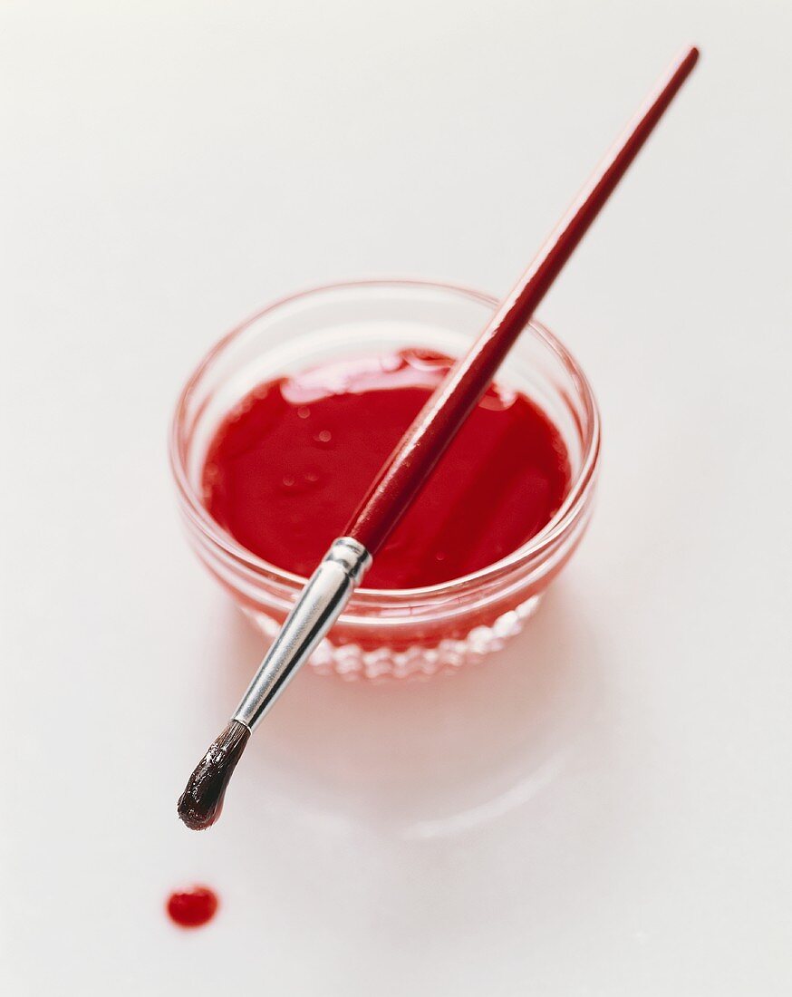Small Glass Bowl of Red Icing with a Paint Brush