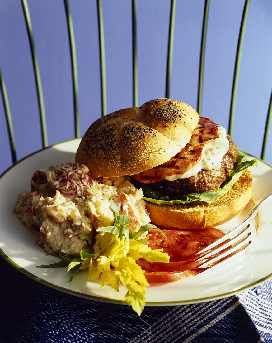 Cheeseburger on a Poppy seed Bun with Potato Salad and Fresh Tomato Slices