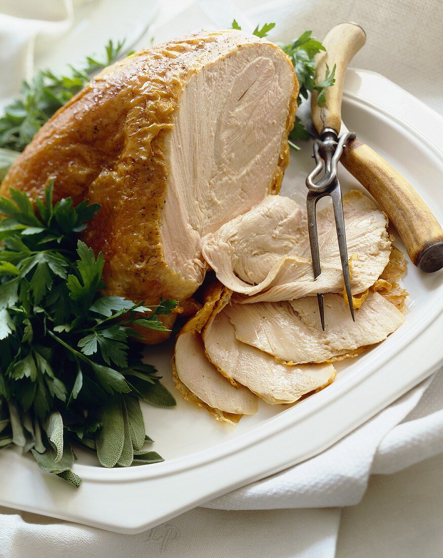 Partially Sliced Roast Turkey Breast on a Platter with Carving Utensils