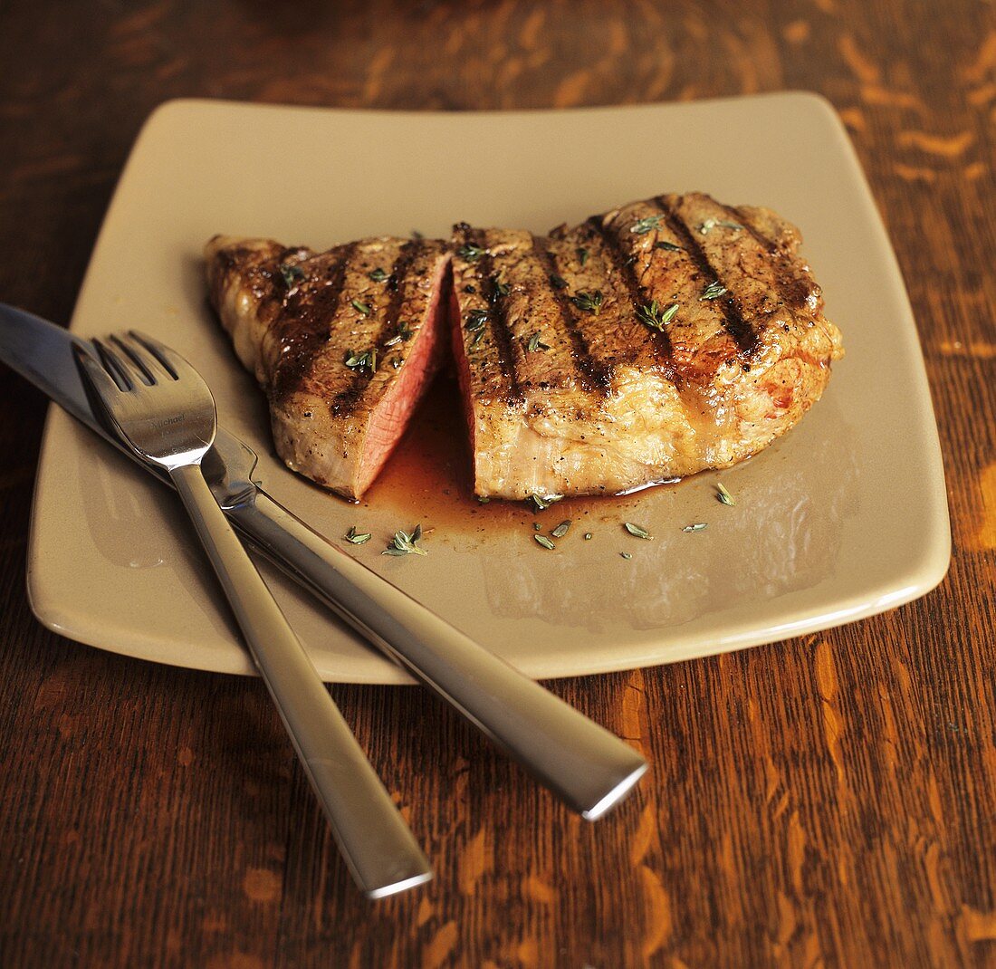 Grilled Steak Sliced on Plate with Fork and Knife