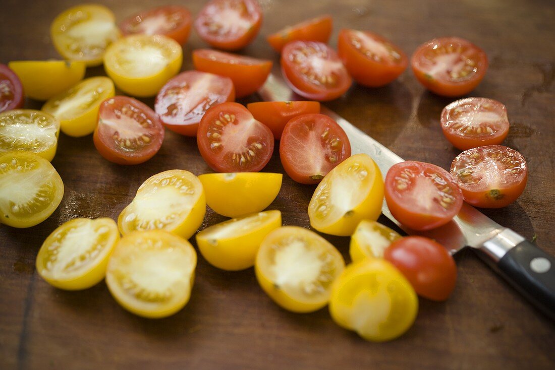 Fresh Yellow and Red Cherry Tomatoes; Halved on Cutting Board with Knife