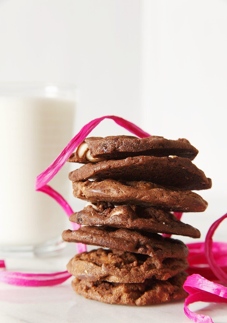 Stack of Chocolate Cookies with Pink Ribbon and Glass of Milk