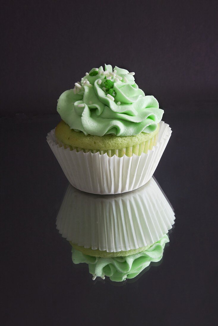 Green Cupcake with Green Frosting and Sprinkles; On Mirrored Surface