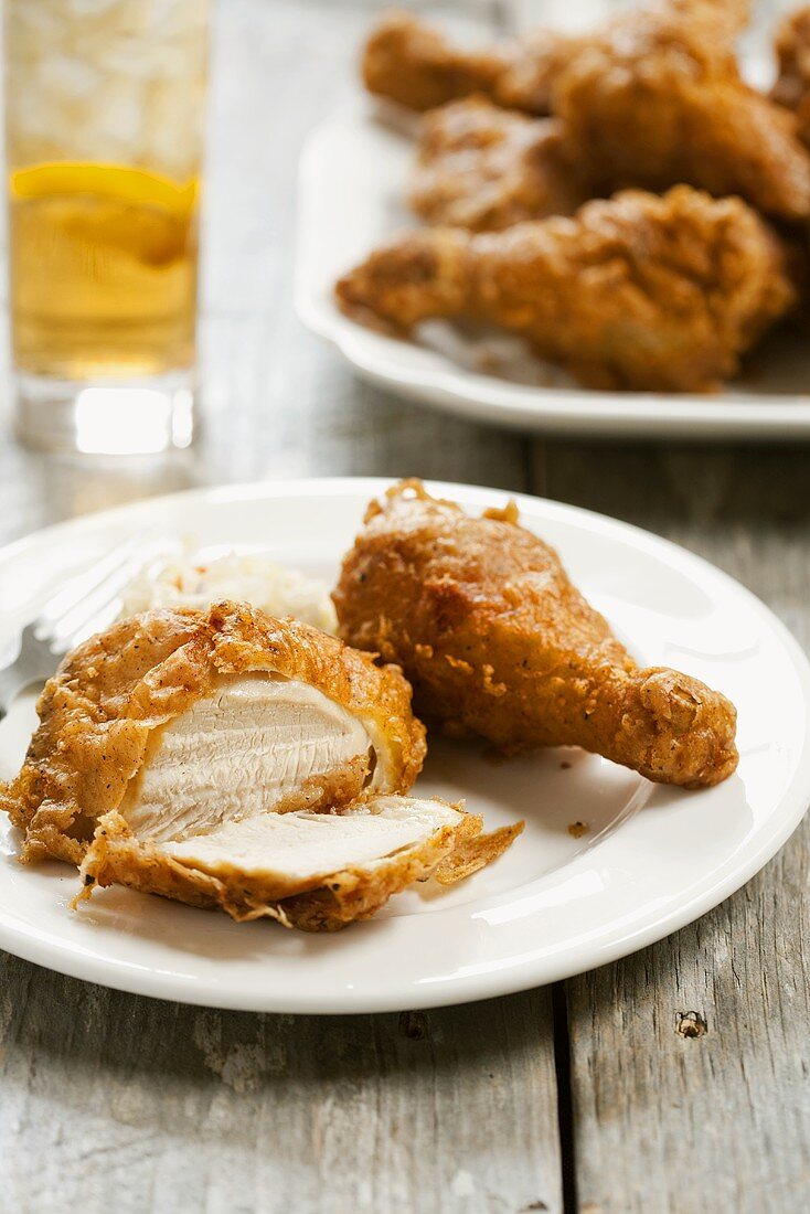 Two Pieces of Battered Fried Chicken on a Plate; One Piece Cut Open