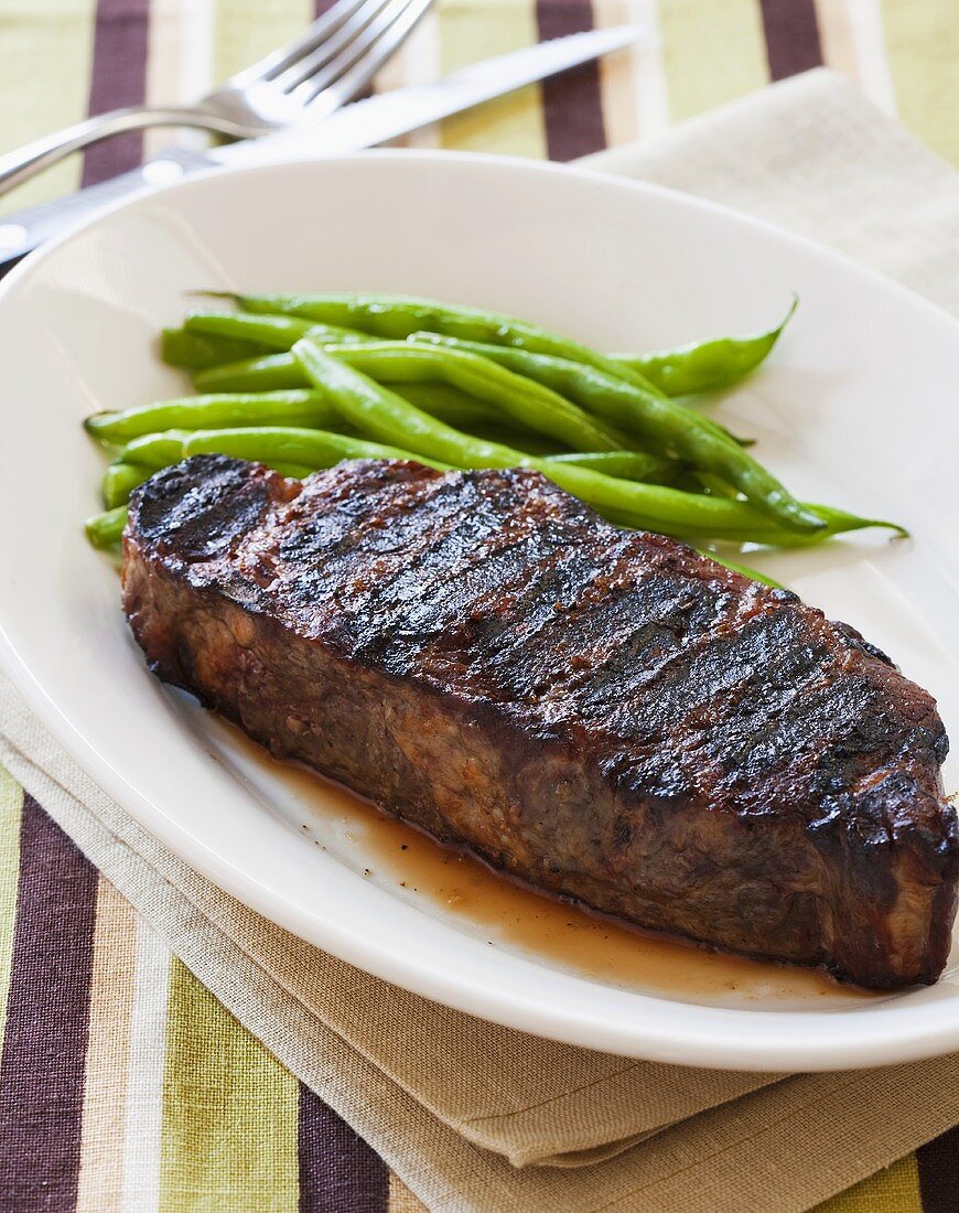 Grilled New York Strip Steak with Green Beans on White Plate