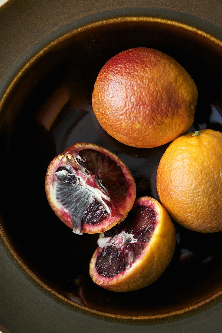 Blood Oranges in a Bowl; Two Whole and One Halved