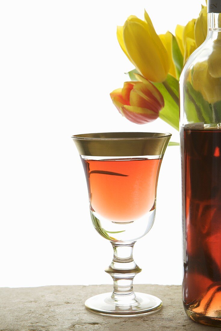 Roseweinglas und Flasche vor Tulpenstrauss