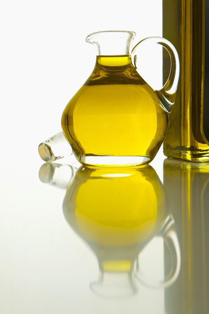 Kaltgepresstes Olivenöl in Karaffe neben Flasche