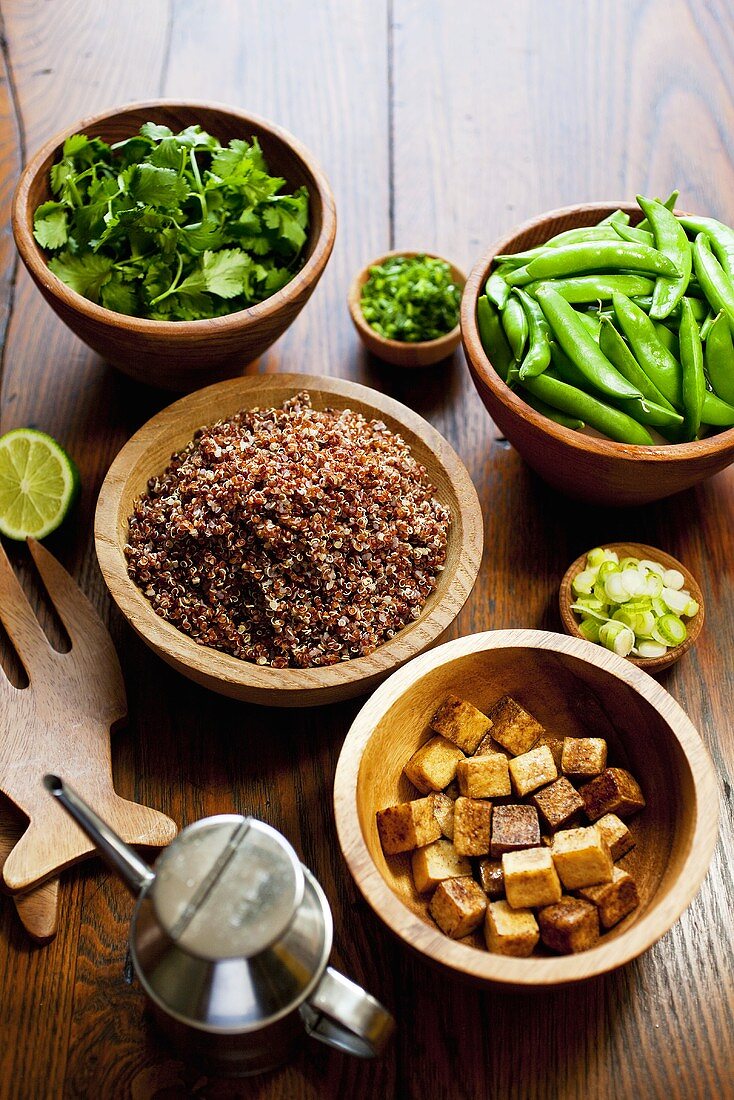 Tofu, Quinoa, Koriandergrün und Erbsenschoten in Holzschalen