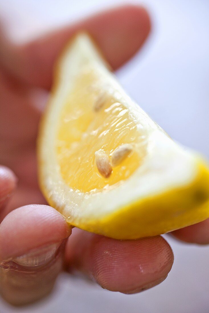 Hand Holding a Lemon Wedge
