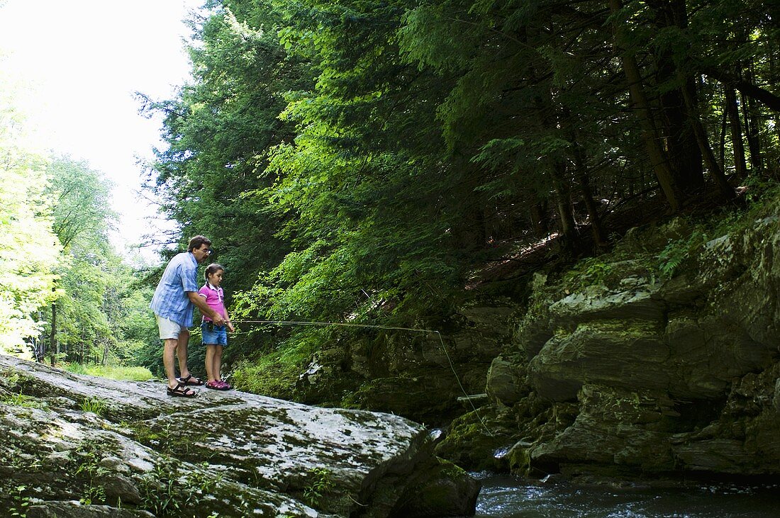 Father Showing his Daughter how to Fish; Fishing off a Rock in a River