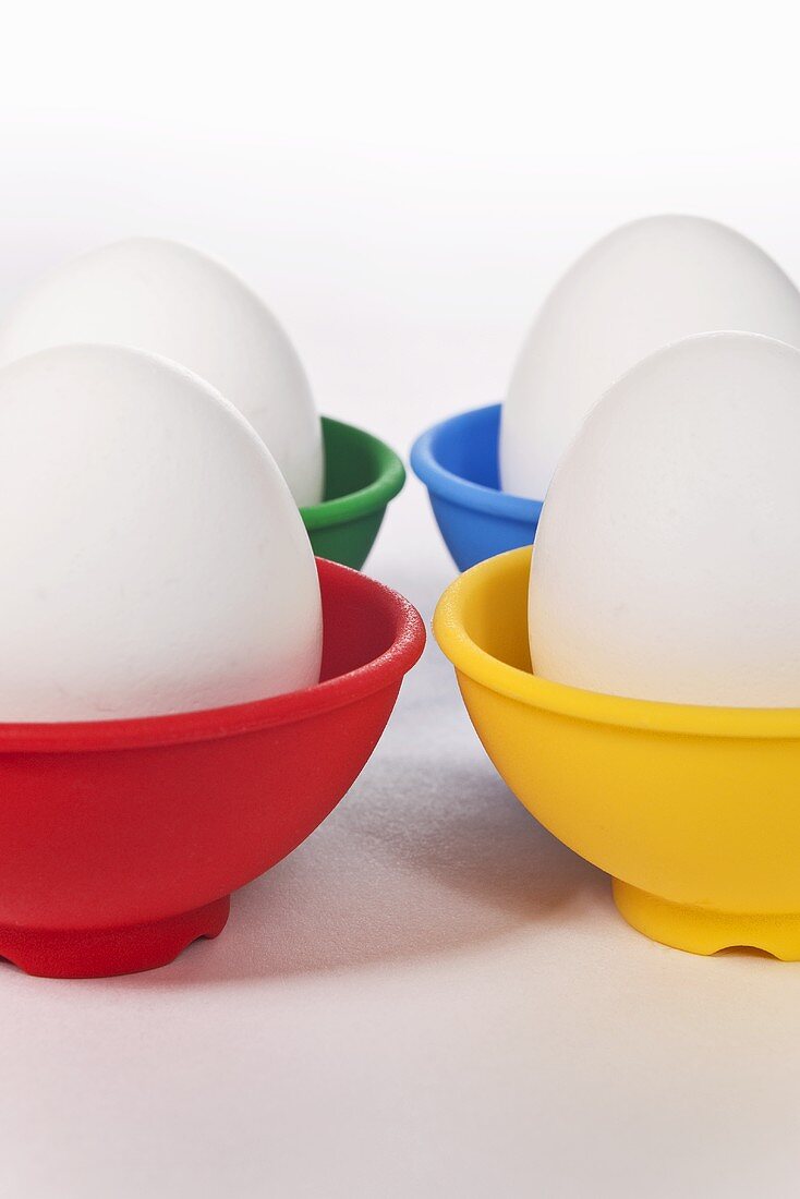 Four White Eggs in Colorful Cups