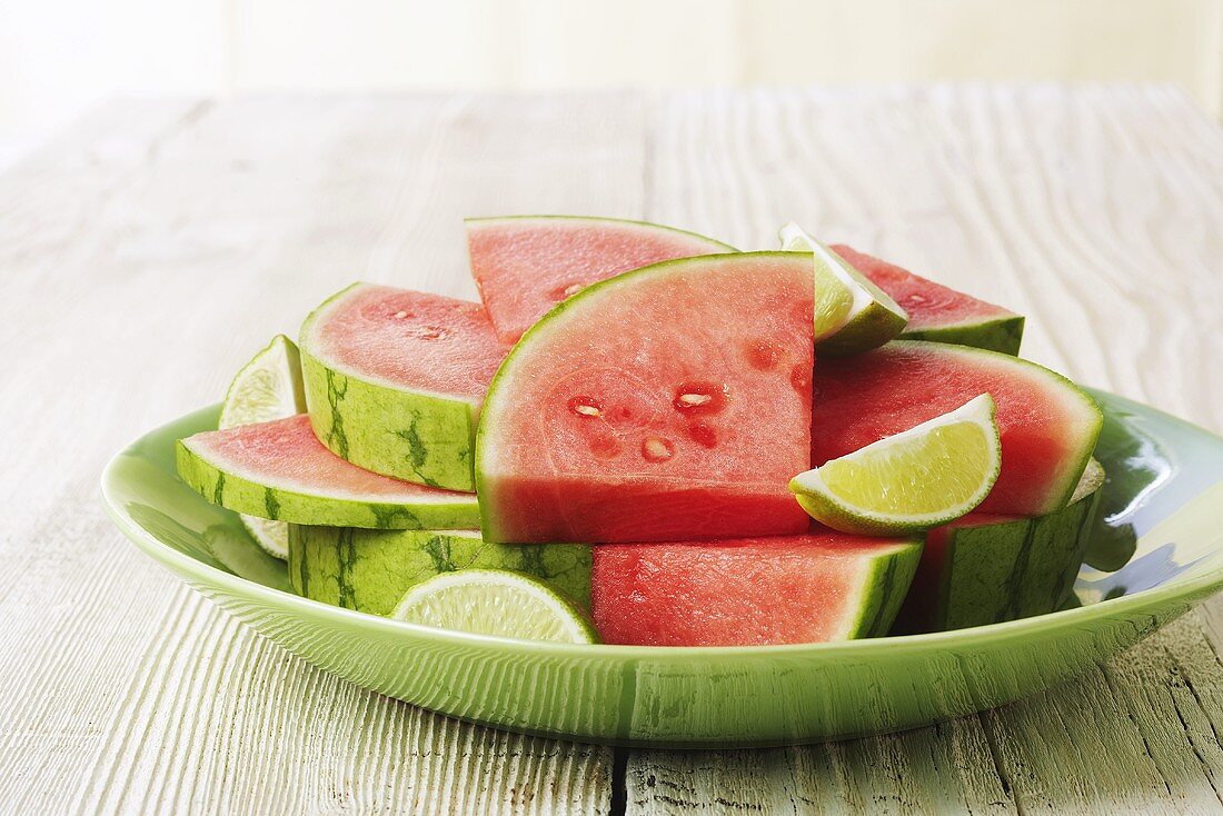 Wassermelonenstücke und Limetten auf Teller