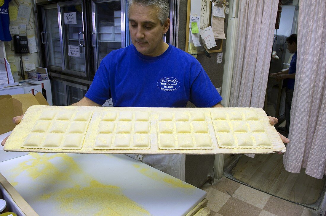 Mann hält Tablett mit frisch gemachten Ravioli (Borgatti's, Little Italy, New York)