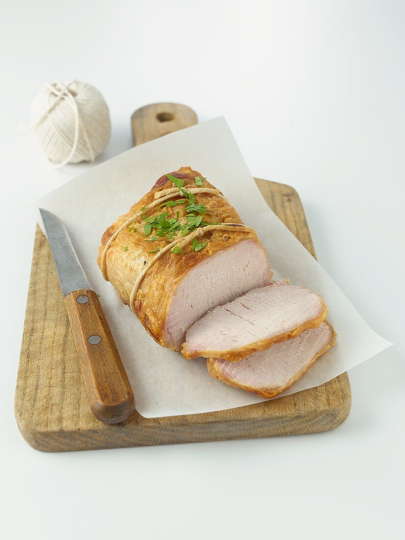 Partially Sliced Pork Roast on Cutting Board with Knife