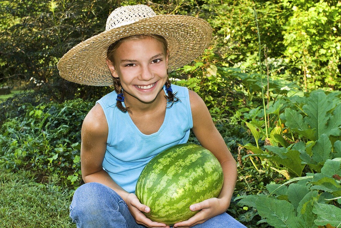 Young Girl Holding a Fresh Picked Watermelon in a Garden