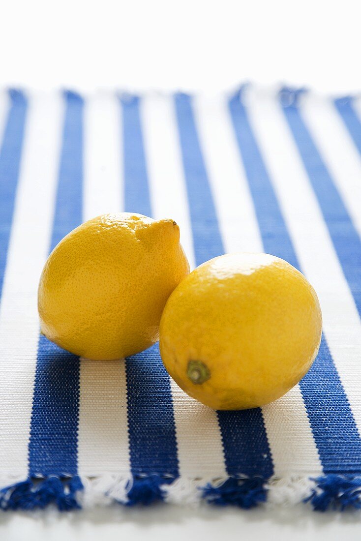 Zwei Zitronen auf blau-weiss gestreiftem Tuch