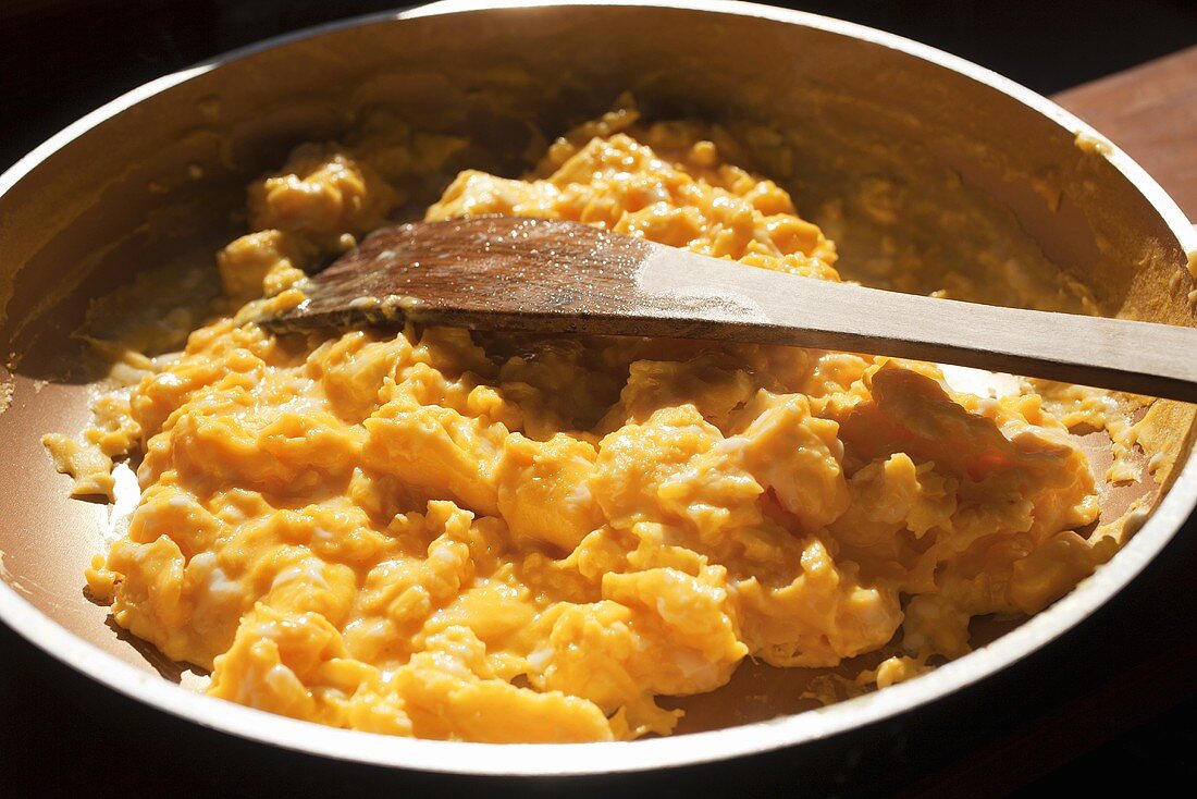 Scrambled Eggs in Frying Pan with Wooden Spatula