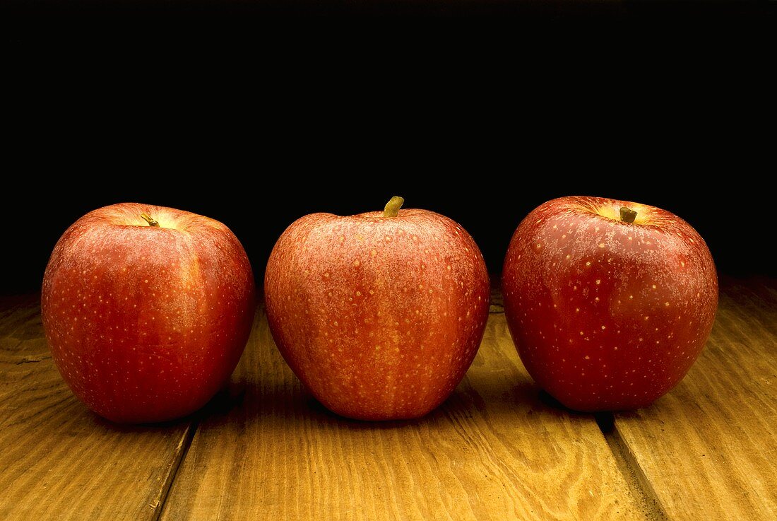 Drei rote Äpfel auf Holztisch