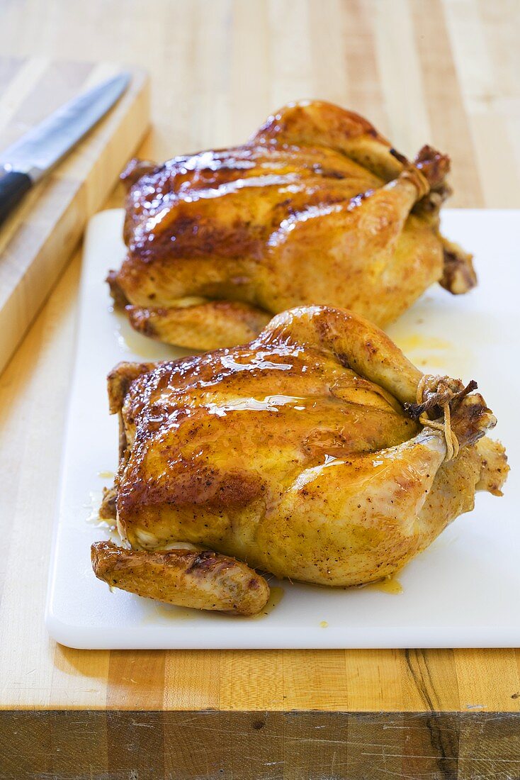 Two Whole Roasted Chickens with a Honey Glaze; On Cutting Board
