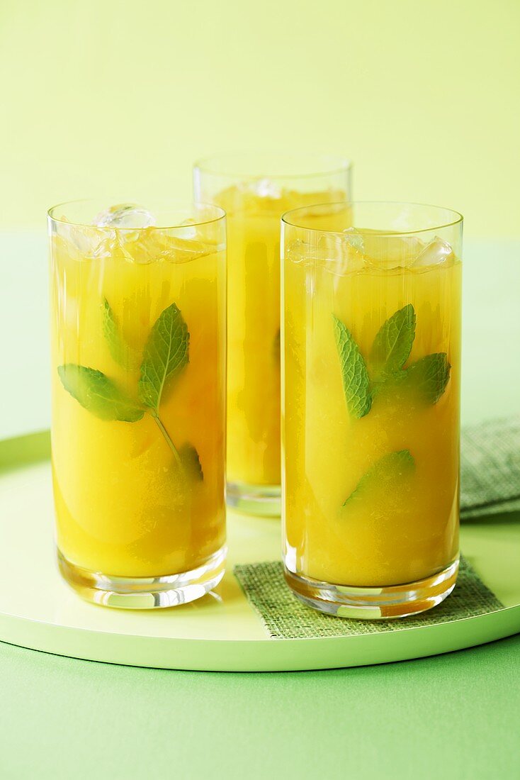 Drei Gläser Orangensaft mit Minze & Eiswürfeln