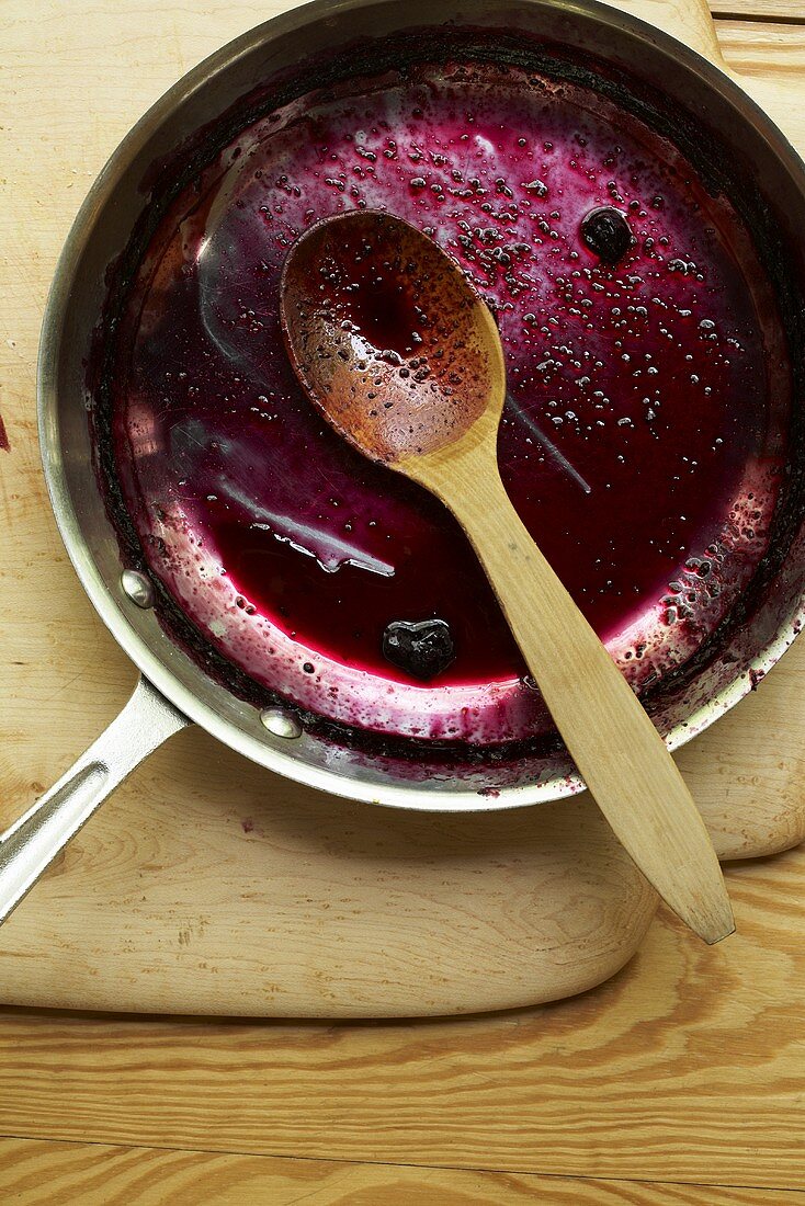 Reste einer Beerensauce in Pfanne mit Holzlöffel