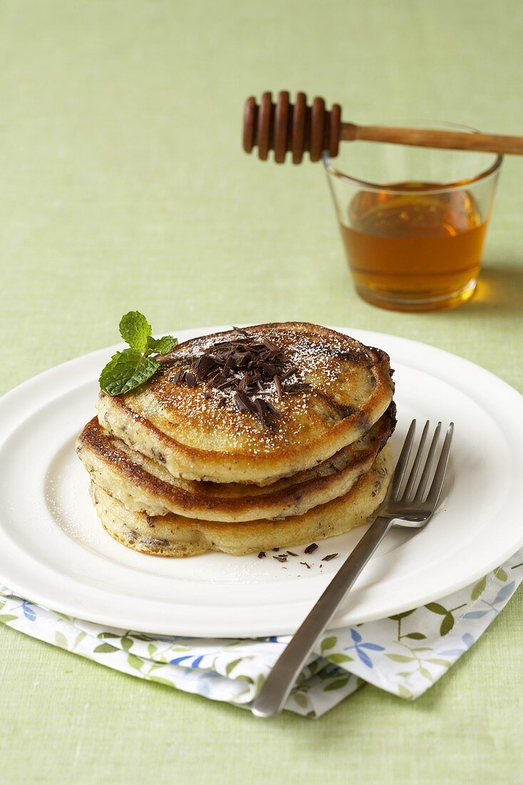 Small Stack of Pancakes Topped with Chocolate Shavings; Syrup with Honey Dipper