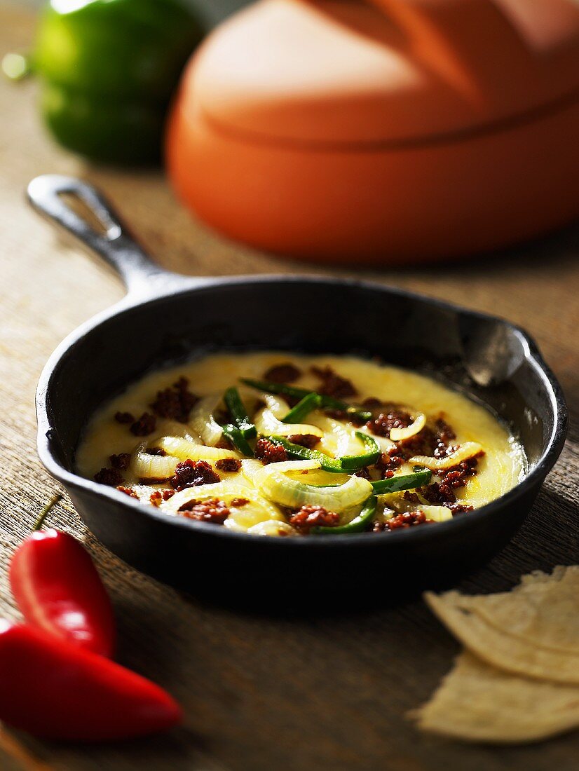 Queso Fundido (Mexican Cheese Dish) with a Onions in a Cast Iron Skillet